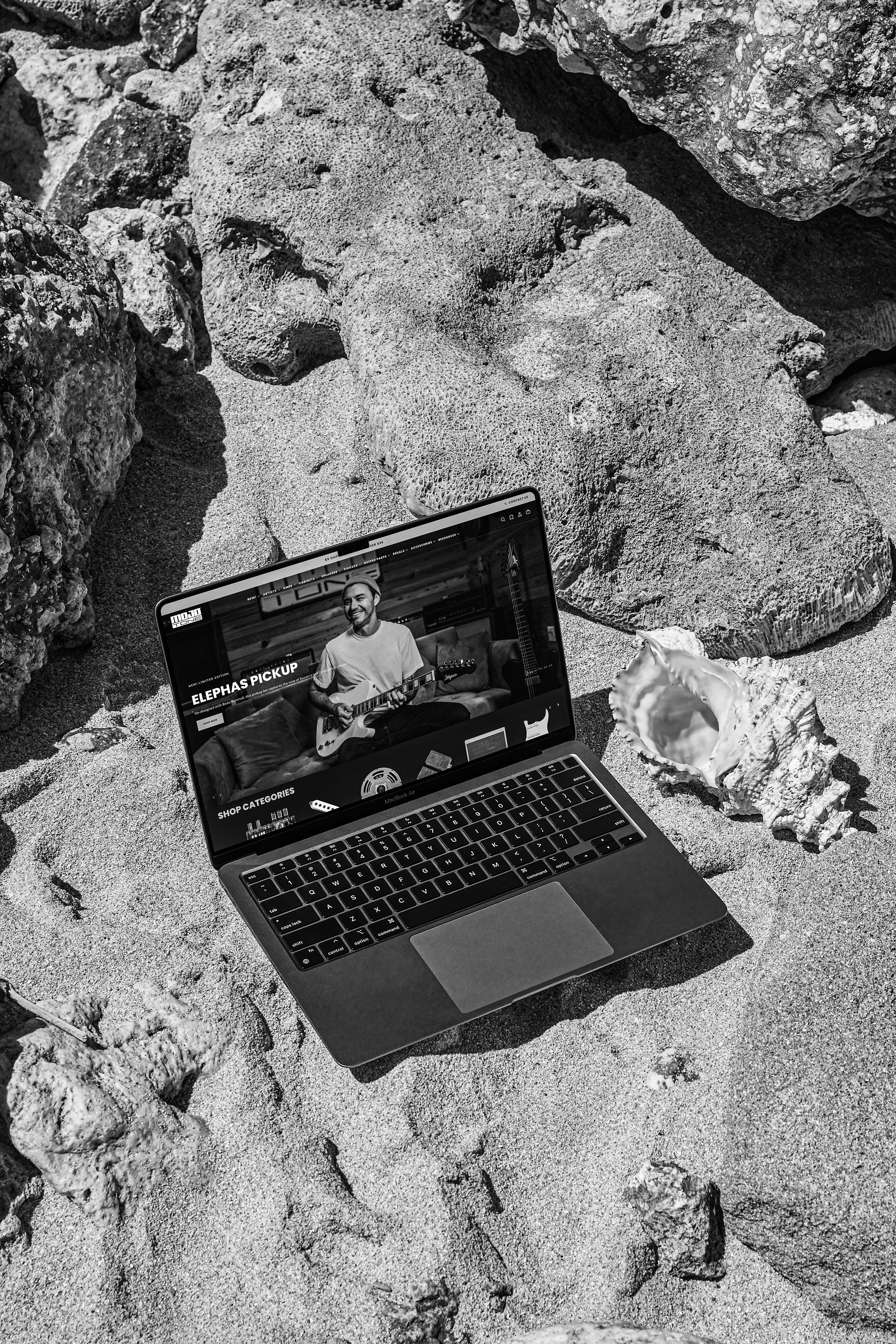 Laptop on a rocky surface with a person playing guitar on the screen